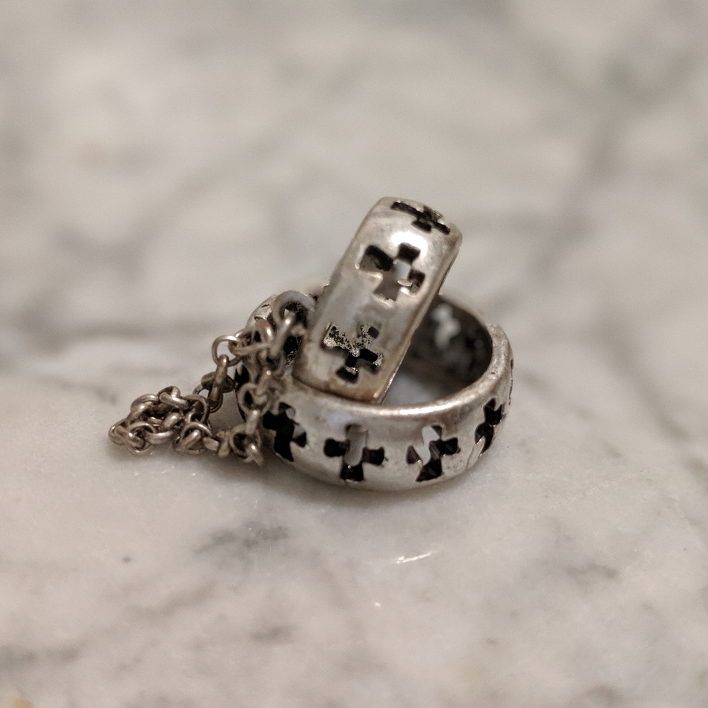 Silver color ring with crosses and chain connecting both together